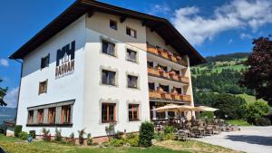 a large white building with tables and chairs at Hotel Dahoam by Miha in Westendorf