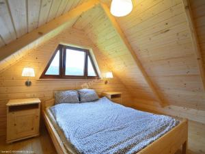 sypialnia z łóżkiem na drewnianym poddaszu w obiekcie Domki Czterech Braci w mieście Grywałd