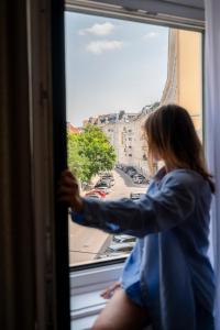 a woman looking out a window at a city at Miki Stays - 200m zum Prater in Vienna