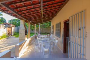a patio with white chairs and tables and a wooden pergola at Recanto do mar in Ilhéus