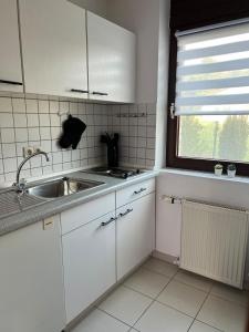 a kitchen with white cabinets and a sink and a window at Fernblick Oase in Meschede