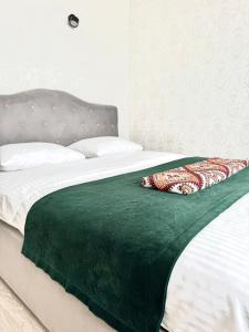 a bed with a green blanket on top of it at Apartments with Dnipro view in Kyiv