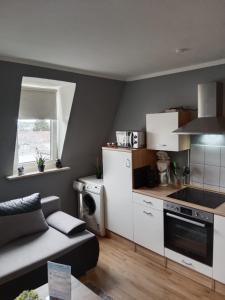 a kitchen with white cabinets and a couch in a room at Katharinas Ankerplatz in Flensburg +5 photos