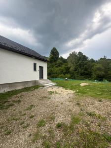 a white building with a door in a yard at Pod Kyčarou in Čabalovce