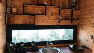 a kitchen with a sink and a large window at MiNi chalet en bois in Menzel Abderhaman