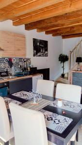 a dining room with a table and white chairs at Au Nid Douillet in Gilocourt