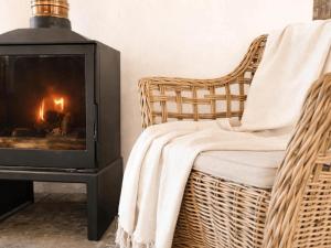 a living room with a fireplace and a wicker chair at Fijnbosch Self-Catering Units in Jacobs Bay