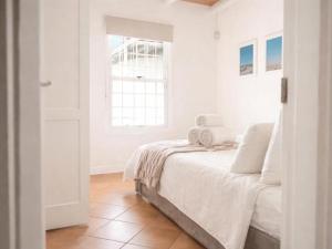 a white bedroom with a bed and a window at Fijnbosch Self-Catering Units in Jacobs Bay +2 photos