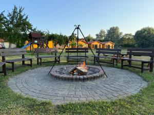 a fire pit in a park with benches and a playground at Willa Aleksander in Rewal