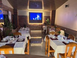 ein Restaurant mit weißen Tischen und einem Fernseher an der Wand in der Unterkunft Hotel Suites Bambú in Minga Guazú