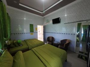 a bedroom with a green bed and a couch at Fathin Hotel Bawean Syariah in Sangkapura