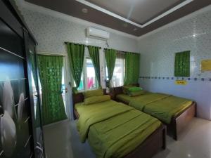 two beds in a room with green curtains at Fathin Hotel Bawean Syariah in Sangkapura