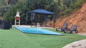 a swimming pool with two chairs and a gazebo at Villa do Alqueidão in Ferreira do Zêzere