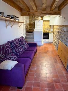 a living room with a purple couch and a kitchen at Casita in Castrojeriz