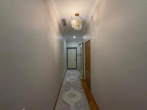 a hallway with a chandelier on the ceiling and a hallway with a door at HomeLand in Almaty