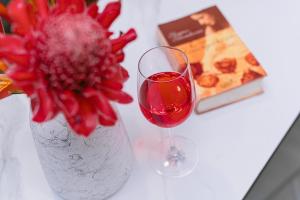 a glass of wine next to a vase with a flower at Vega Haven in Matara