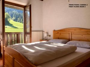 a bedroom with a large bed with a large window at Casa vacanze Ravascletto in Ravascletto