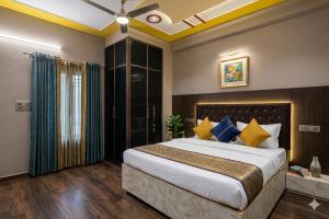 a bedroom with a large bed with blue and yellow pillows at Hotel Grand Heaven in Tājganj