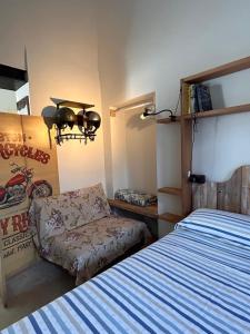 a bedroom with a bed and a couch and a chair at Tati's Home CHARME & BIKERS in Mandello del Lario