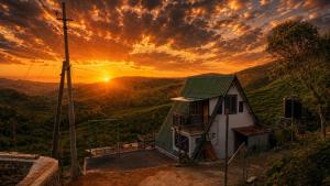 a house on a hill with a sunset in the background at Kalathil Guest House in Vagamon