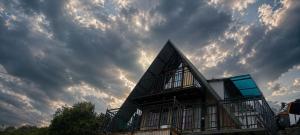 a house on a hill with a cloudy sky at Kalathil Guest House in Vagamon