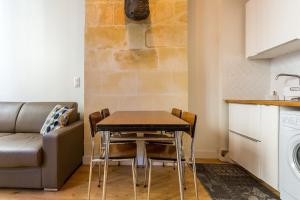 a kitchen and dining room with a table and a couch at Appartement quartier St Michel climatisé près des quais avec parking in Bordeaux +10 photos