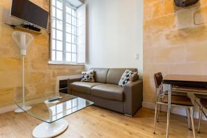 a living room with a couch and a table at Appartement quartier St Michel climatisé près des quais avec parking in Bordeaux