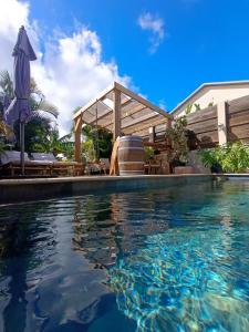 a swimming pool with an umbrella and the water at Monstera Lodge in Saint-Louis