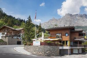 a building on the side of a road with a mountain at Guesthouse Hotel Between in Chamoson
