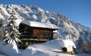 a building in the snow with a snow covered mountain at Guesthouse Hotel Between in Chamoson +113 photos