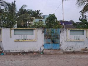 a white building with a blue door and a fence at Guna stay in Virāmpattinam