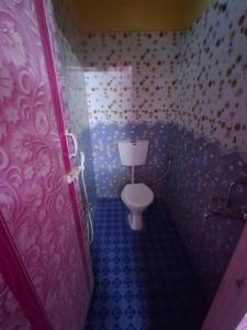 a small bathroom with a toilet in a room at Guna stay in Virāmpattinam