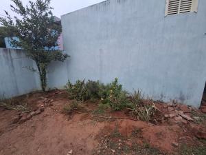 a garden with a wall and a tree next to it at Guna stay in Virāmpattinam