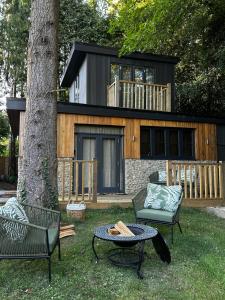 a house with a tree and two chairs and a table at Tree Top & Bluebell Cottages in Grange Road Station