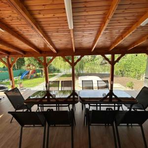a patio with four tables and chairs under a wooden roof at Nándi Jakuzzis Vendégház in Gyomaendrőd