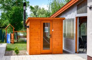 a wooden shed with a door in a yard at Nándi Jakuzzis Vendégház in Gyomaendrőd