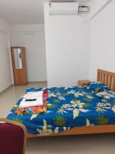 a bedroom with a bed with a blue comforter at Uthram Avenue in Tāmarakulam