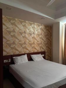 a bedroom with a white bed and a wall with a sqor at 9 orchid Parbhat royal in Gobindgarh