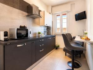 a kitchen with black cabinets and a microwave and a table at Mellini Living in Misano Adriatico