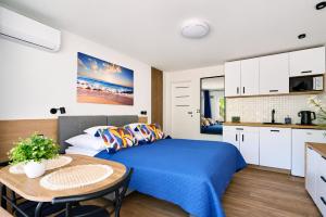 a bedroom with a bed and a table and a kitchen at Baltic Sand - Apartamenty I Pokoje Władysławowo in Władysławowo