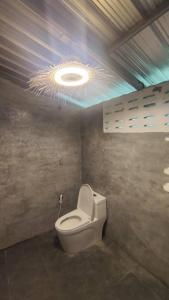 a bathroom with a toilet with a light on the ceiling at Laena Homestay in Ko Yao Noi