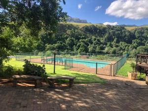 a swimming pool with two benches and a fence at Ledges Retreat in Bergville