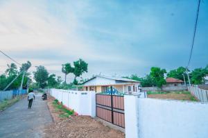 a man walking down a street next to a fence at Rani Alfred in Viramanikkatevanturai