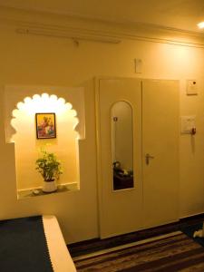 a bedroom with a mirror and a door with a plant at Mahadev Bhavan in Chittaurgarh