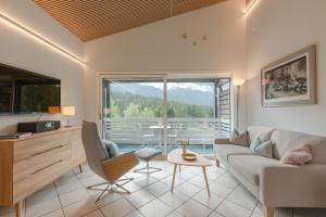 a living room with a couch and a large window at Zuhause in den Alpen Ihre Ferienwohnung mit Hallenbad und Sauna in Lenzerheide