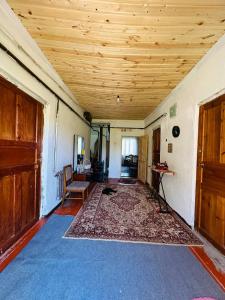 a living room with a wooden ceiling and a rug at Uruyat Nomad guesthouse in Naryn