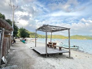 a picnic table and bench on a beach next to the water at Pasir Homestay in Gili Gede