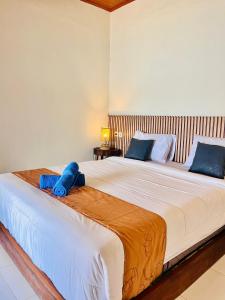 a large bed with a blue stuffed animal on it at Pasir Homestay in Gili Gede