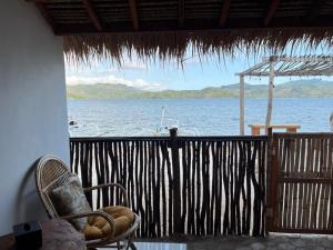 a room with a chair and a view of the water at Pasir Homestay in Gili Gede
