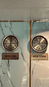 two clocks on a wall with a new york and moscoon at Diltoj Hotel Tashkent in Tashkent